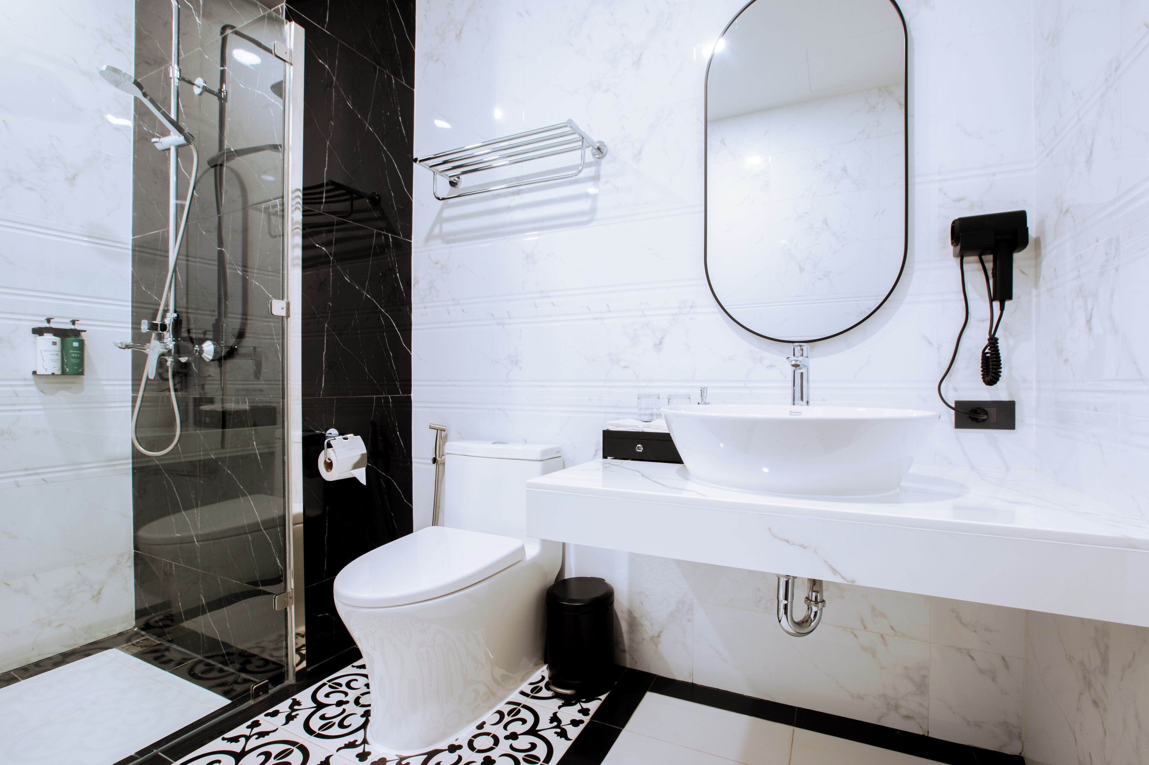 A modern bathroom with a glass-enclosed shower, a white toilet, a white sink, and a large mirror.
