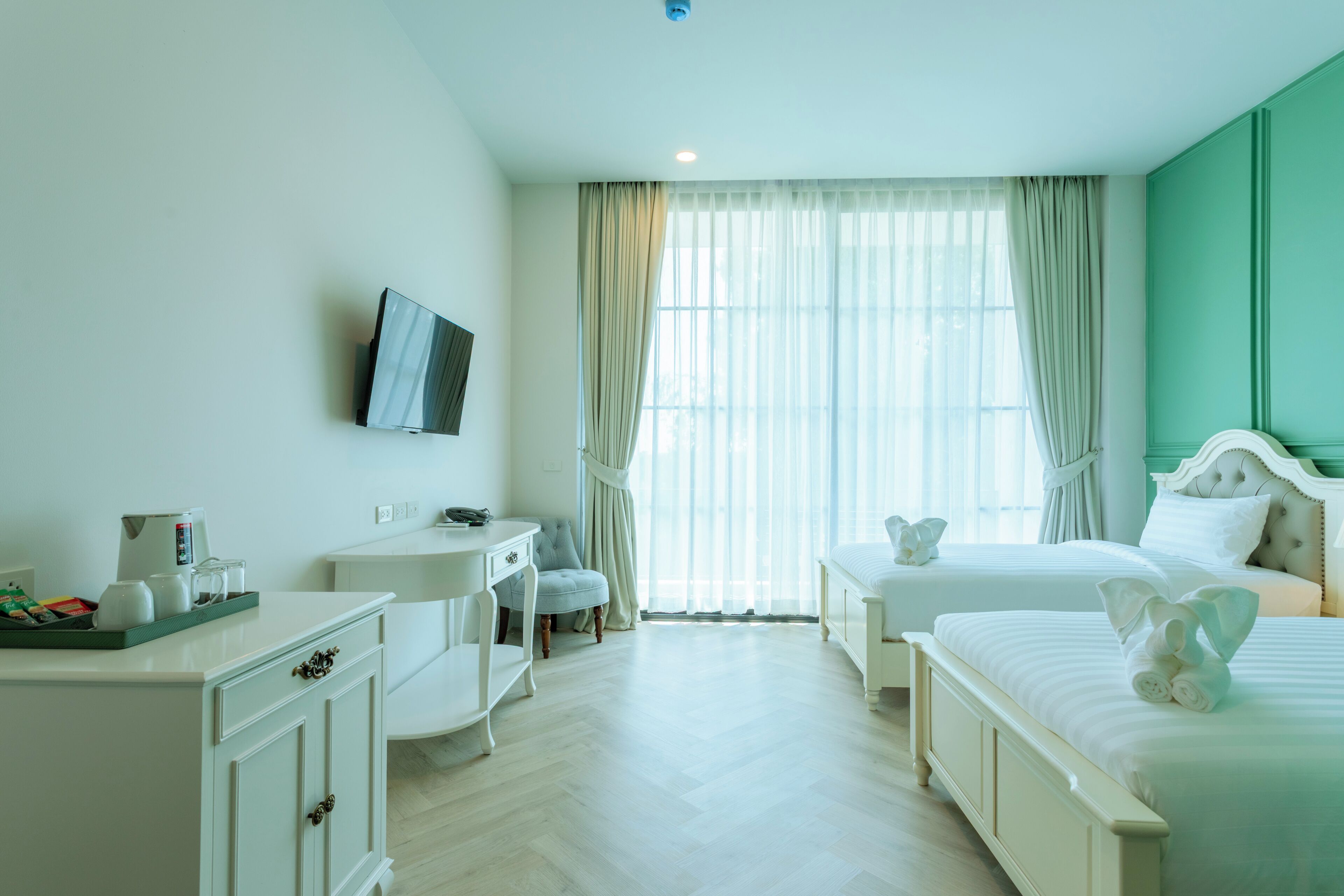 A hotel room with a bed, bedside table, chair, desk, and a television on the wall.