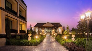 A building with a covered entrance, a paved pathway, and decorative lighting. - Paradhevi Boutique (Ban Dung)