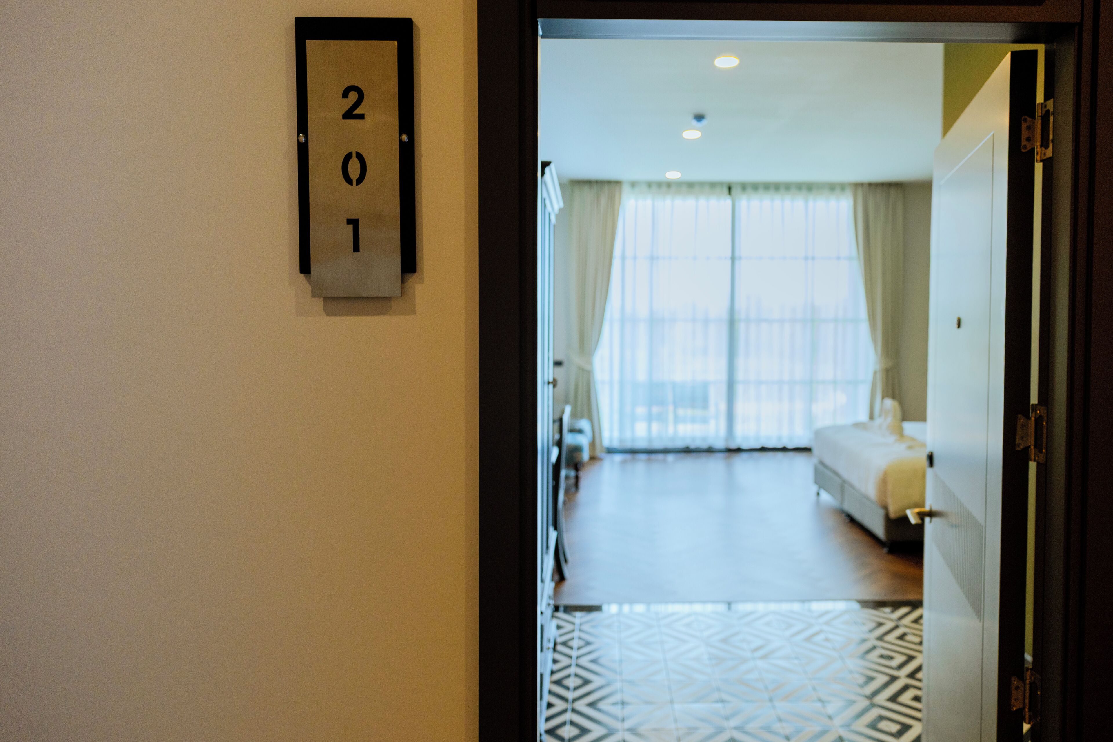 A hotel room with a bed, a nightstand, and a window with curtains.