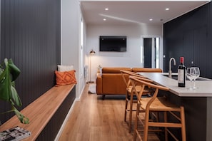 A modern kitchen with a wooden bench, a sofa, and a dining area with chairs.