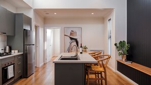 A modern kitchen with a central island, stainless steel appliances, and a dining area with wooden chairs. - Style, space & comfort in the heart of Currie (Currie)