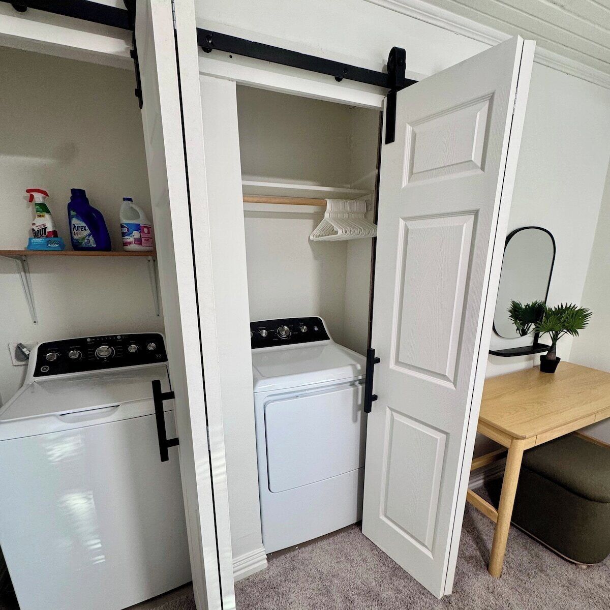 A compact laundry room with a washing machine, dryer, and storage shelves.