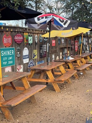 Taules de picnic de fusta a l'aire lliure amb un cartell de Shiner City Limit, població 2069.