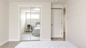 Une chambre à coucher comprenant un lit, un placard avec porte coulissante et un petit bureau avec une chaise.