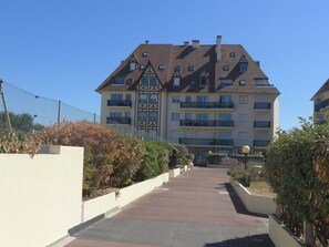 Un edificio residencial de varios pisos con fachada simétrica, varios balcones y una entrada central.
