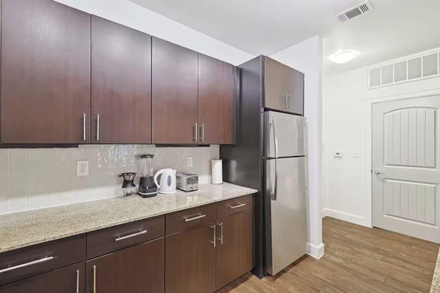 Una cocina moderna con alacenas de madera oscura, un refrigerador de acero inoxidable y una encimera de granito.