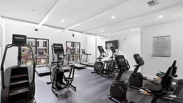 A gym with treadmills, elliptical machines, and a TV on the wall.