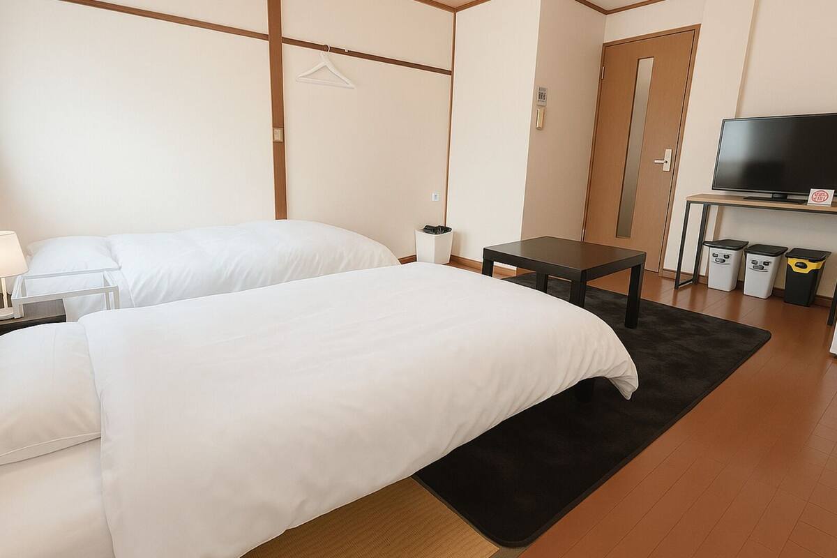 Ein Hotelzimmer mit zwei Betten, einem Schreibtisch, einem Fernseher und einem Kleiderschrank.