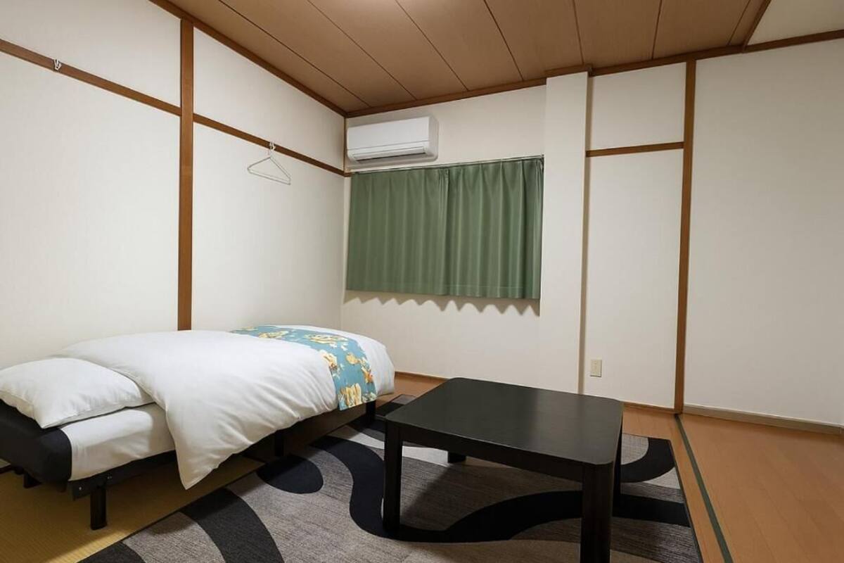 Ein Zimmer mit einem Bett, einem Tisch und einer Kleiderstange.
