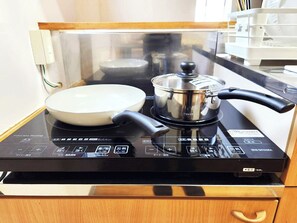 Una cocina con una placa de inducción, una olla y una sartén.