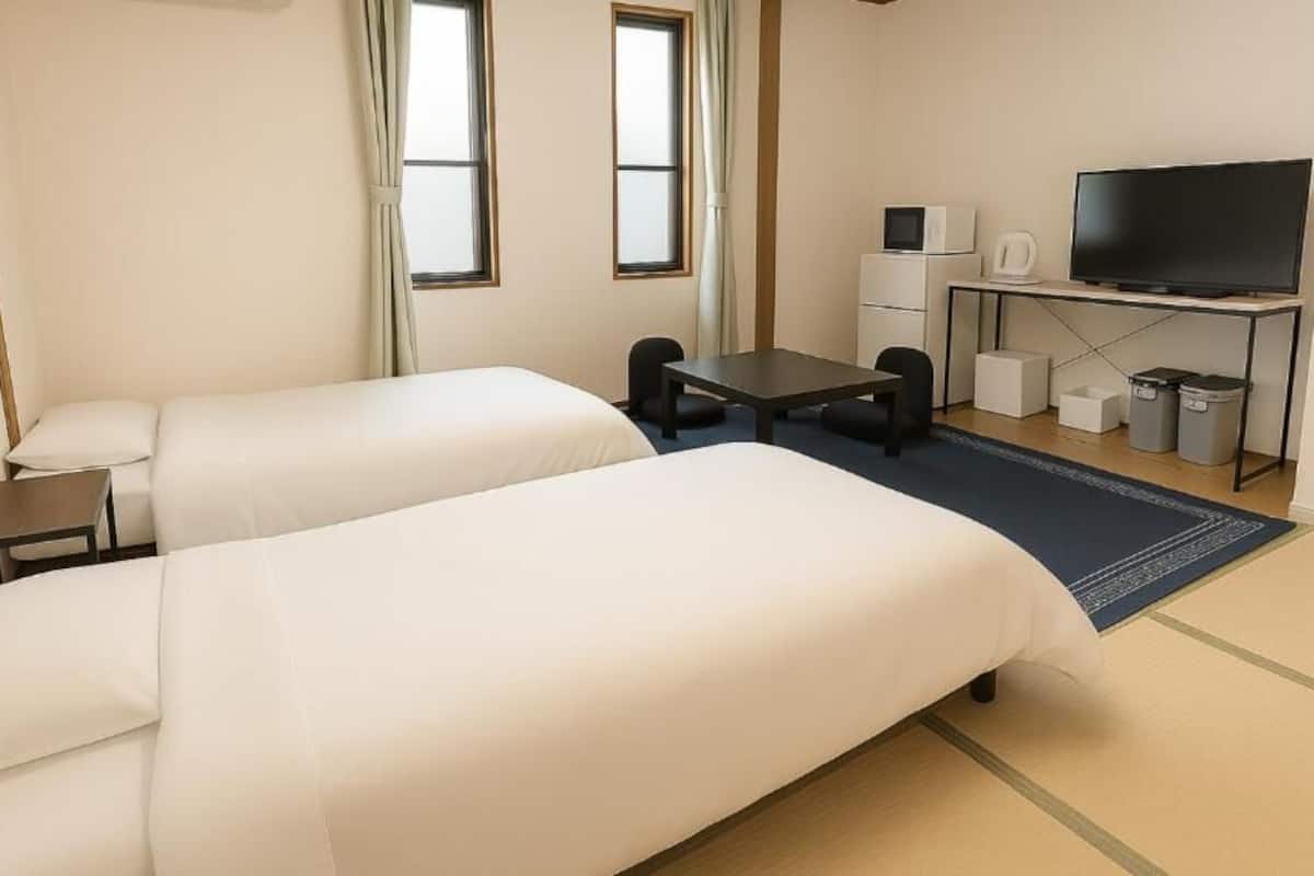 Ein Hotelzimmer mit zwei Betten, einem Schreibtisch, einem Fernseher, einer Mikrowelle und einer Kaffeemaschine.