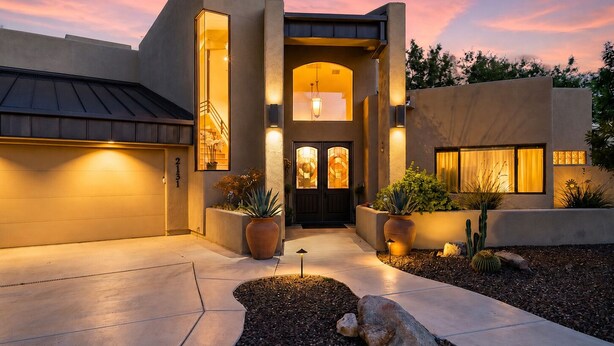 A modern house with a large driveway, a garage, and a well-lit entrance. - Waterfront Clubhouse at Antelope Hills (Prescott)
