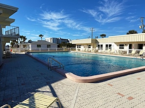 A swimming pool with lounge chairs and a lifeguard stand.