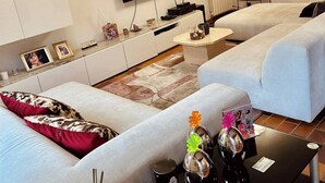 Una sala de estar moderna con dos sofás, un televisor de pantalla plana, una mesa de centro y una mesita auxiliar.