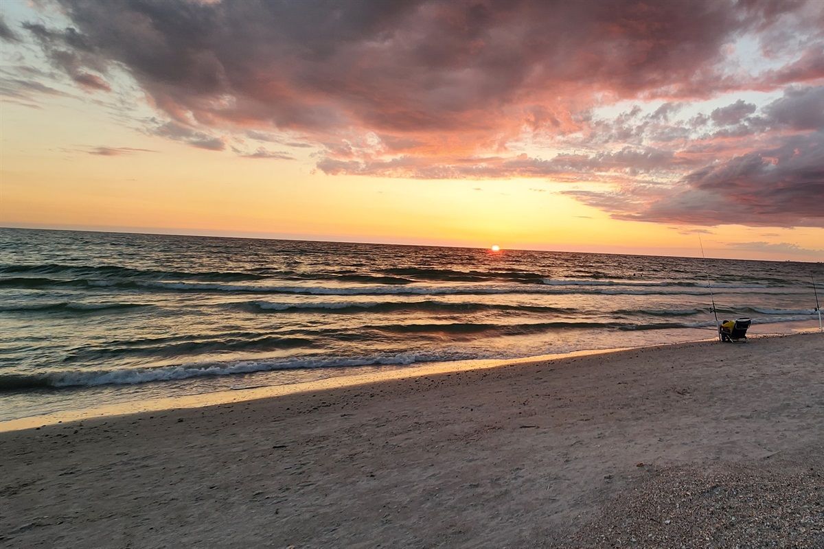 A beach with waves and a sunset.