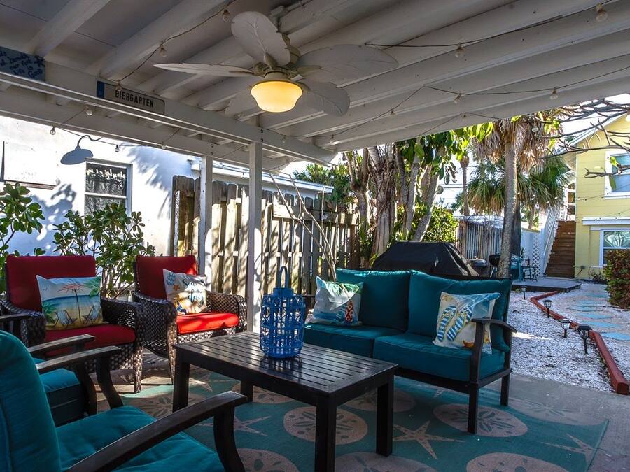 Un patio al aire libre con mobiliario, un ventilador de techo y un cartel que dice 'BIERGARTEN'.