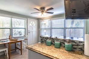 A kitchen with a granite countertop, a ceiling fan, and a window with blinds. - Southern PAG Beach House Bungalows (St. Pete Beach)