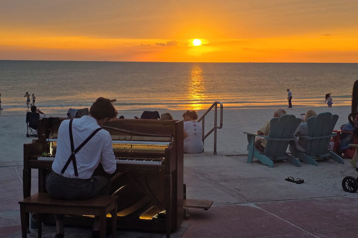 Una presentación de piano frente al mar, con vistas al atardecer.