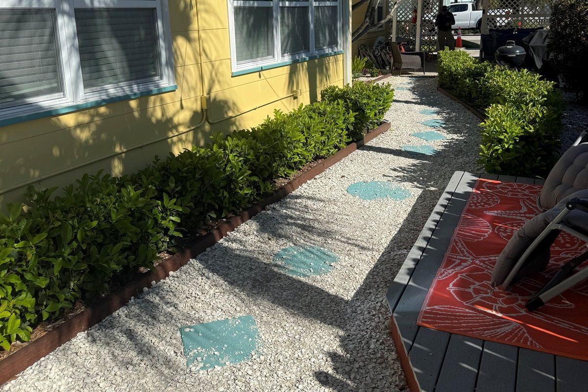 A pathway leading to a house with a gravel surface and decorative tiles.