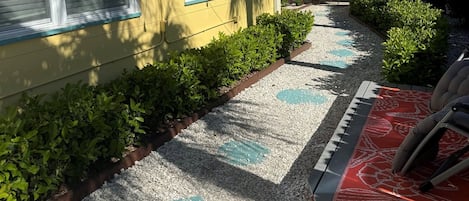 A pathway leading to a house with a gravel surface and decorative tiles.