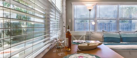A dining area with a wooden table, chairs, and a window with blinds.