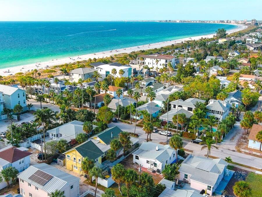 A coastal residential area with houses, palm trees, and a beach.
