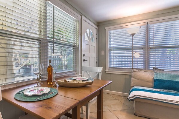 A cozy room with a wooden table set for dining, a bench with cushions, and a door with a window. - Southern PAG Beach House Bungalows (St. Pete Beach)