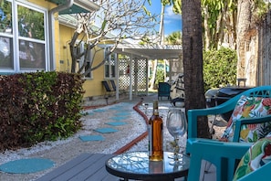An outdoor patio area with a table, chairs, and a bottle of wine. - Southern PAG Beach House Bungalows (St. Pete Beach)