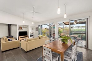 Ein modernes Wohnzimmer mit Kamin, Sofas, einem Fernseher und einem Essbereich mit Tisch und Stühlen.