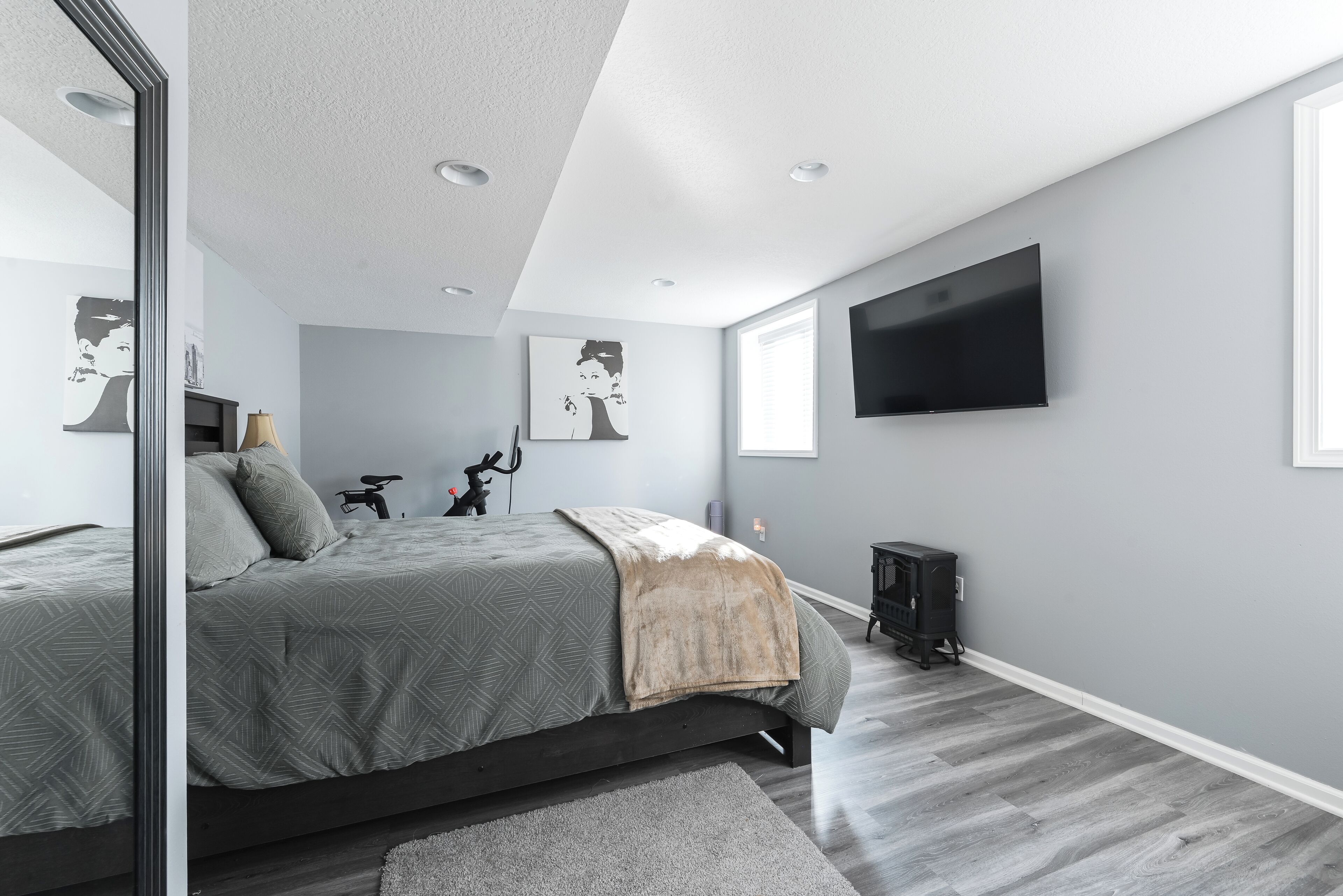 A modern bedroom with a large bed, a flat-screen TV, and artwork on the walls.
