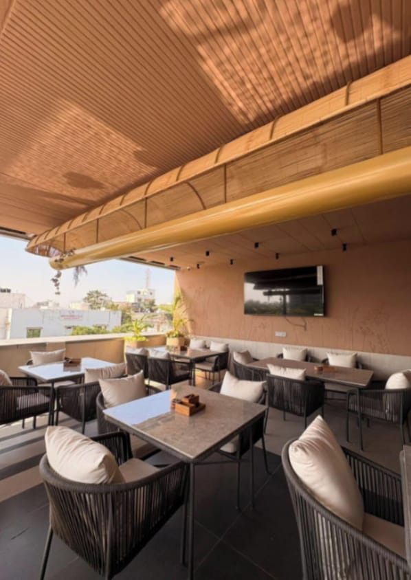 An outdoor seating area with wicker furniture and a flat-screen TV mounted on the wall.