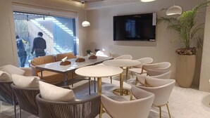 Un espace repas moderne doté d’une grande table, de sièges confortables et d’un téléviseur fixé au mur.