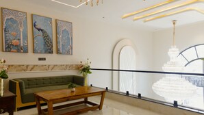 Un hall moderno con un sofá verde, una mesa de centro de madera y pinturas decorativas.