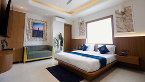 Una habitación de hotel moderna con una cama grande, un ventilador de techo, un televisor y obras de arte en las paredes.