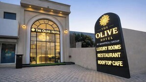 Hotel Olive, con un cartel que enumera servicios como habitaciones de lujo, un restaurante y un café en la azotea.