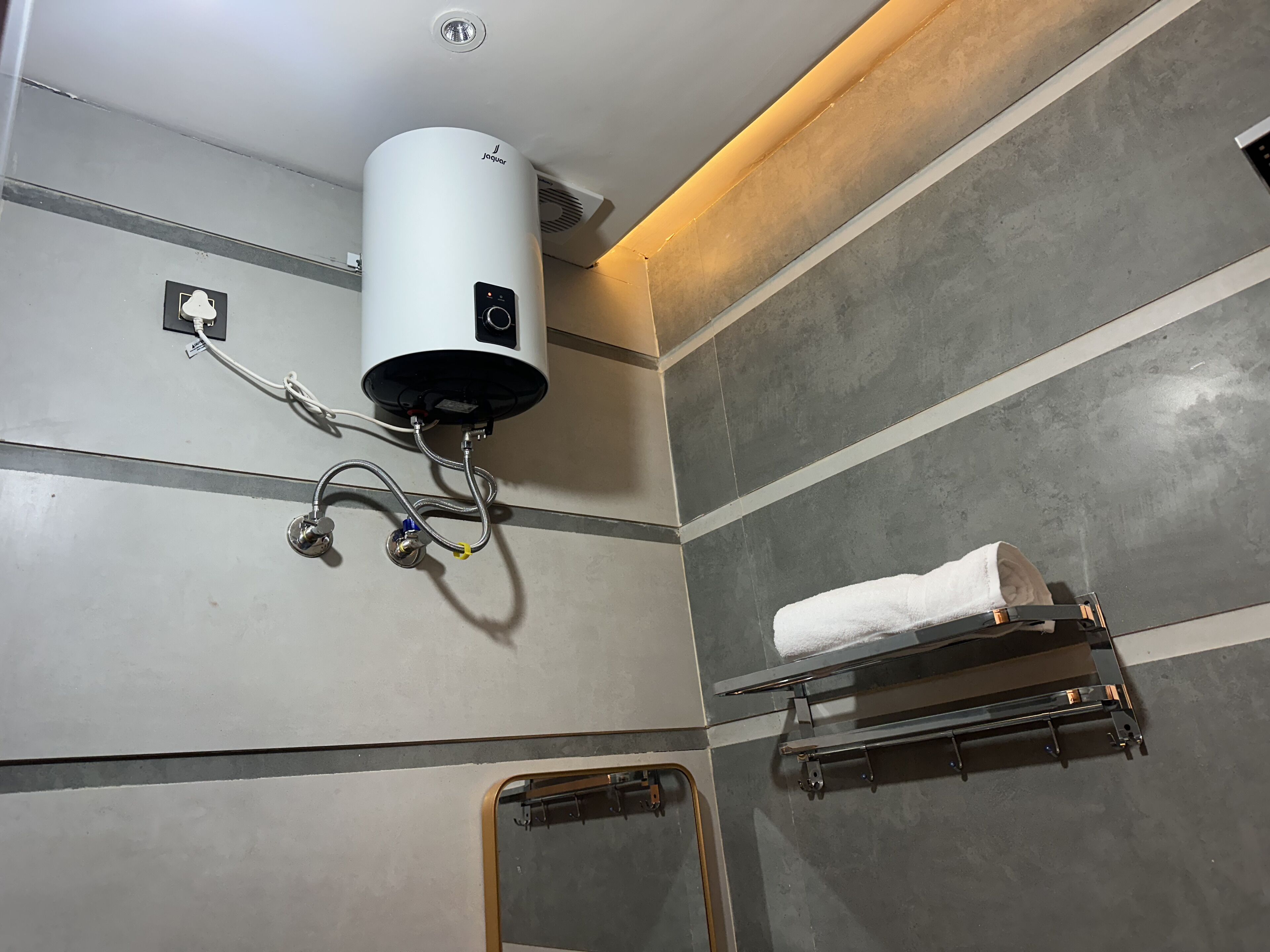 A bathroom with a white heater, towel rack, and a mirror.