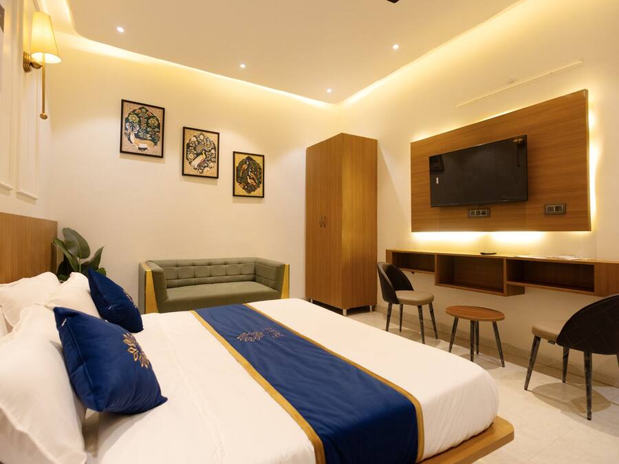 Een hotelkamer met een groot bed, een bank, een bureau en een televisie die aan de muur is bevestigd.