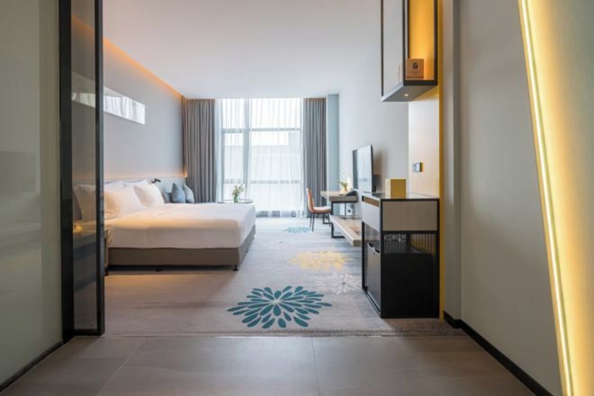 A hotel room with a bed, a desk, a chair, a TV, and a window.
