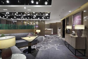 Un moderno vestíbulo de hotel con una zona de estar, un mostrador de recepción y una alfombra estampada.