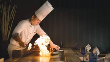 Un chef cocinando sobre una parrilla con llamas.