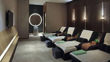 A spa room with massage chairs, a TV, and a circular light fixture.