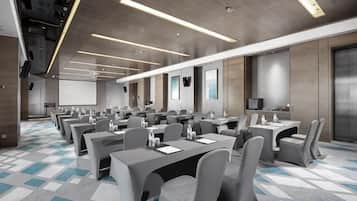 A conference room with multiple tables and chairs, a projector screen, and a large screen on the wall.