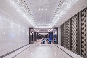 Un pasillo con piso reflectante, paneles decorativos en la pared y varias puertas que dan a habitaciones.