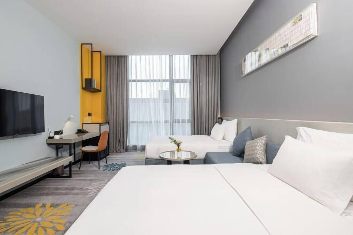 A modern hotel room with a large bed, a desk, and a television.