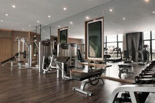 Un gimnasio moderno con diversos equipos de ejercicio, espejos amplios y suelo de madera.