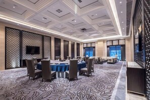 Un salón de conferencias con una mesa grande, sillas y una televisión de pantalla plana.