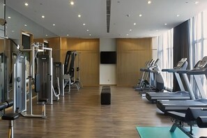 A gym with treadmills, weight machines, and a large mirror. - Wyndham Jinjiang (Jinjiang)