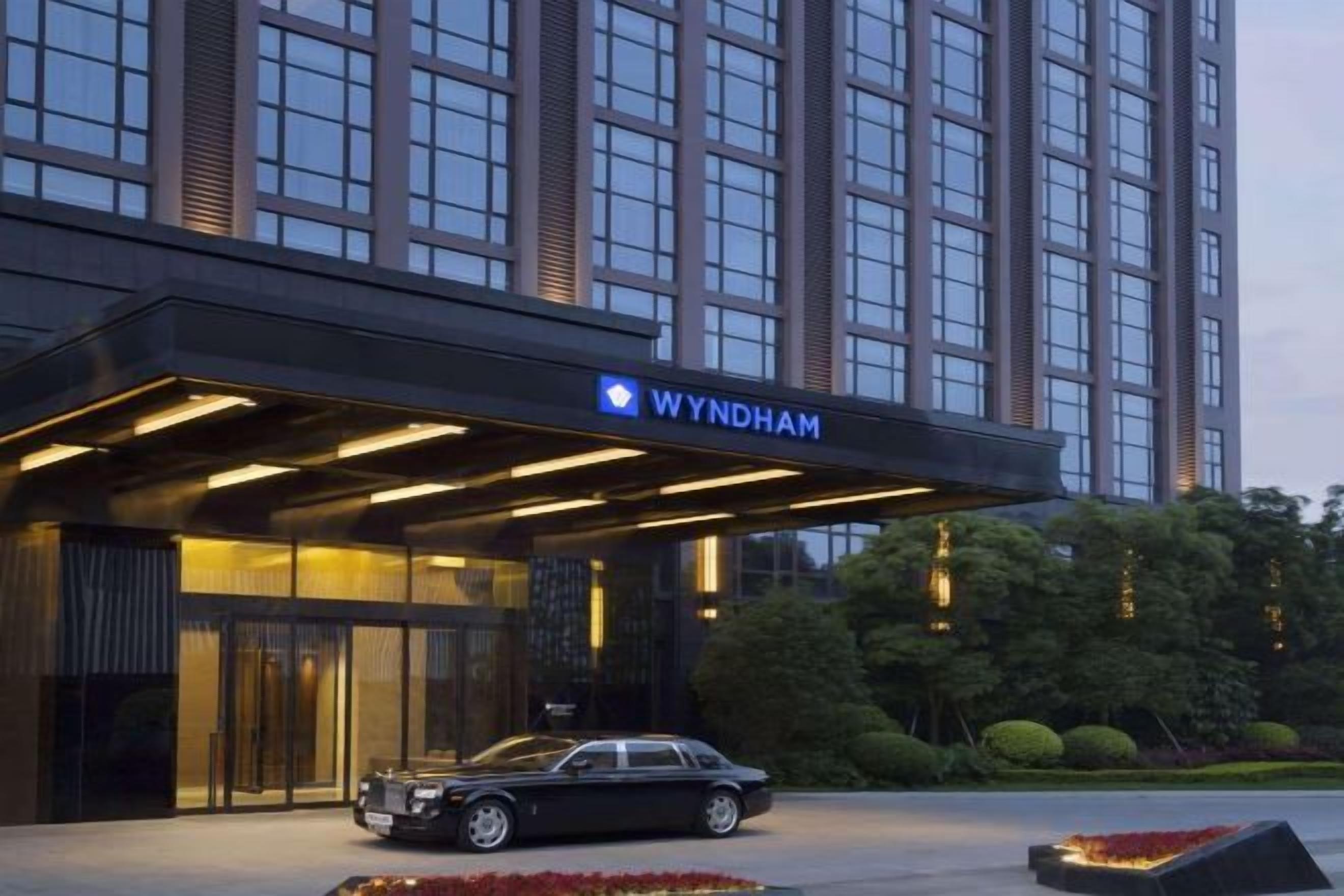 A hotel entrance with a modern design, a car parked in front, and a well-lit facade.