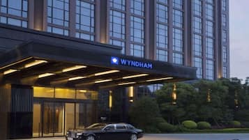 A hotel entrance with a modern design, a car parked in front, and a well-lit facade.